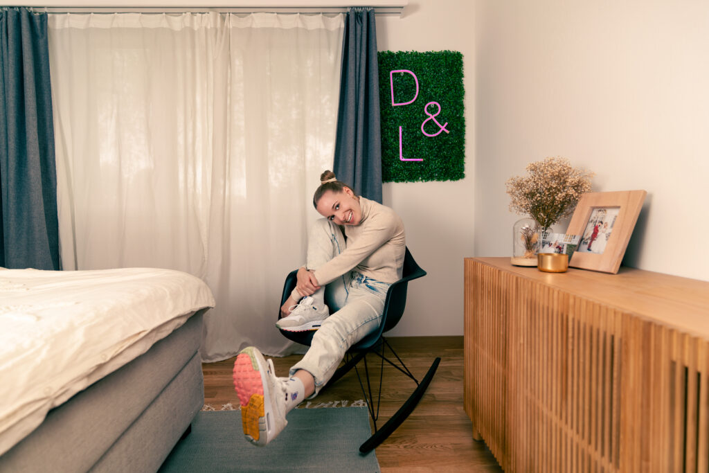 Junge Frau in einem Zimmer, sitzend auf einem Schaukelstuhl.