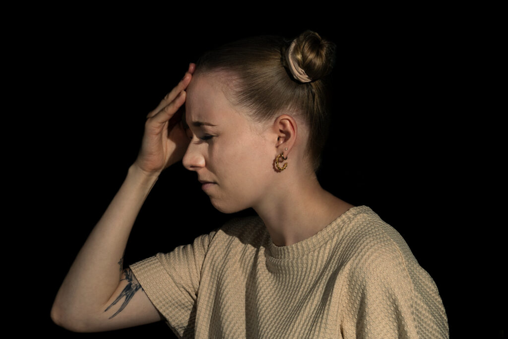 Portrait einer jungen Frau, die sich an den Kopf fasst.